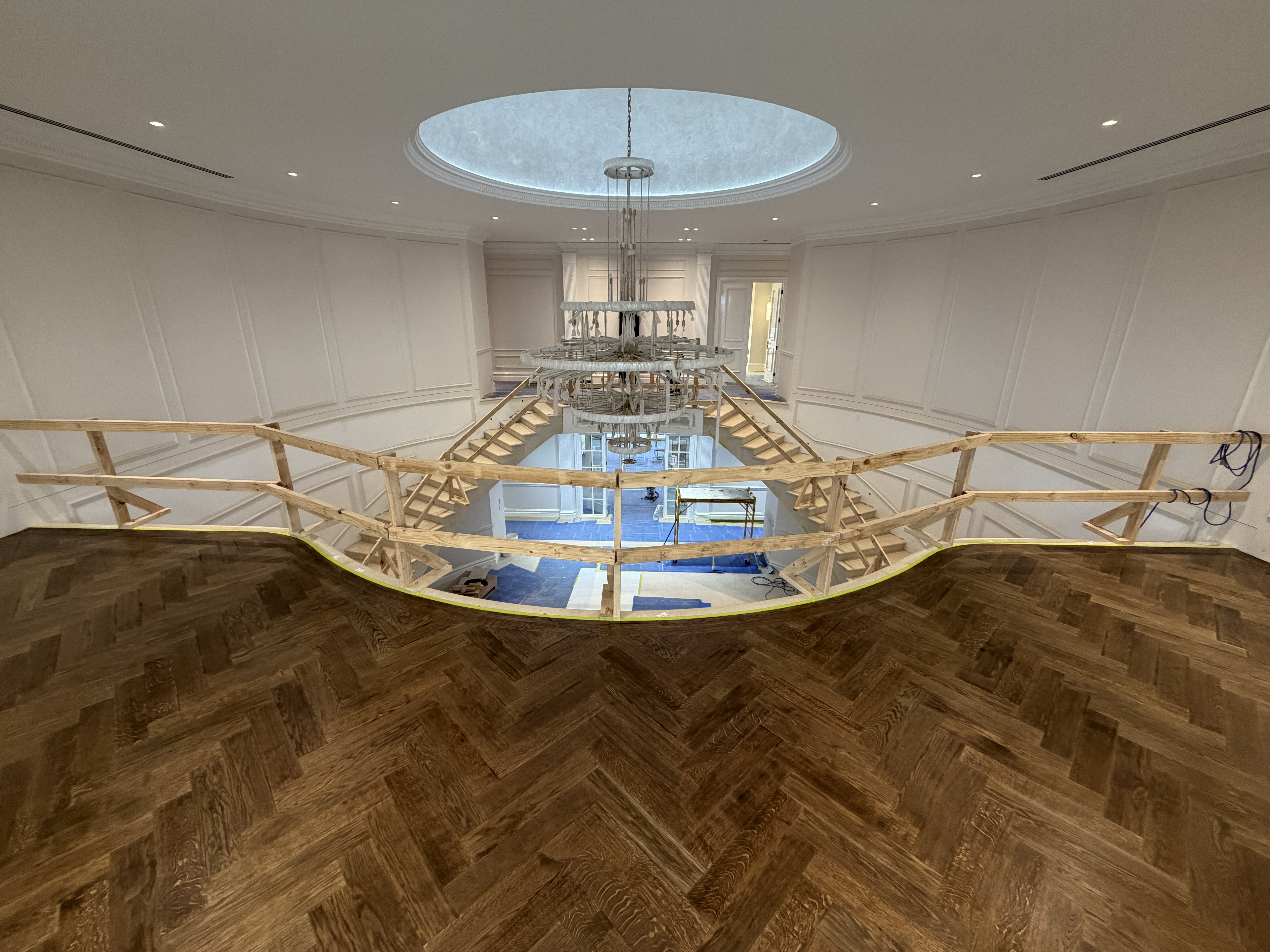 Herringbone parquet floor installed in a grand residence beneath a domed skylight